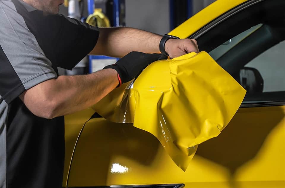 Yellow vinyl wrap being installed on a vehicle