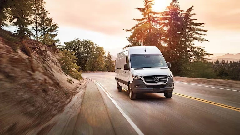 White Mercedes-Benz Sprinter Van driving down a road